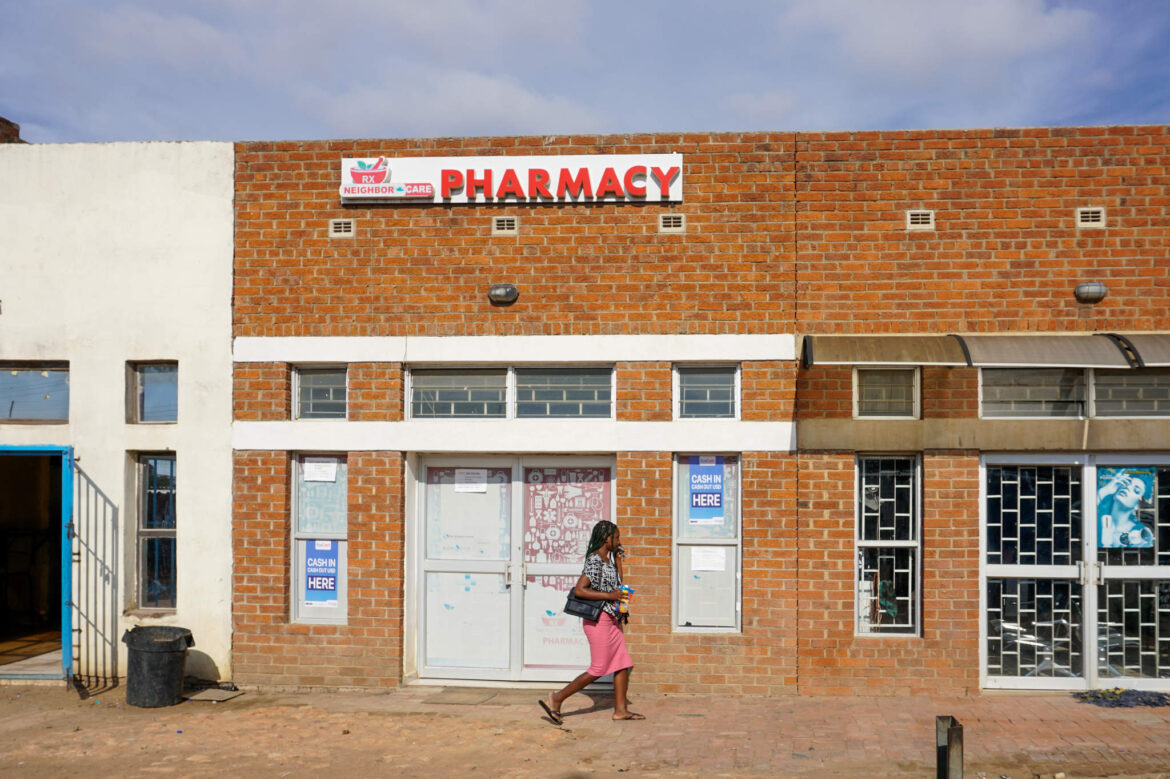 A woman walks past a pharmacy and health facility in Harare. Most Zimbabweans face significant challenges in accessing basic health care, with 93% unable to afford health insurance, according to the Association of Healthcare Funders of Zimbabwe. For many, the only option is purchasing antibiotics from informal medicine stalls, often without prescriptions or proper guidance.
